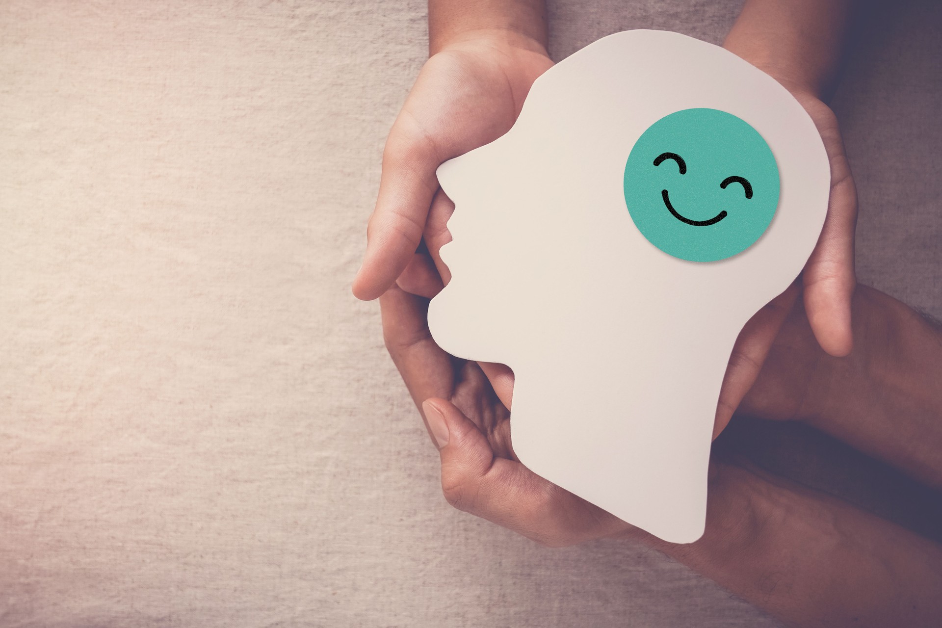 Adult and child hands holding smile face in brain paper cutout, happy hormones, brain chemicals, positive mental health concept